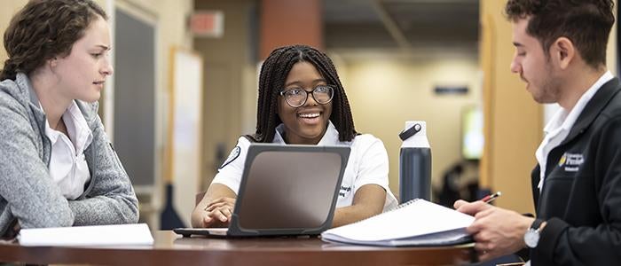 three nursing students meeting at a table with laptop.