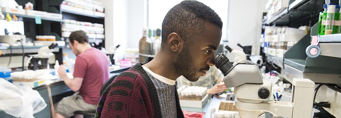 student looking into microscope in bio-science lab