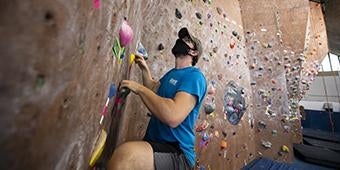 student using Climbing Wall in Trees Hall on Pitt campus