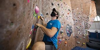 student using Climbing Wall in Trees Hall on Pitt campus.