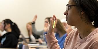 students raising hands in classroom