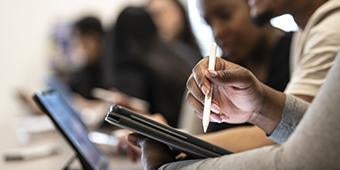 student using tablet and laptop in classroom