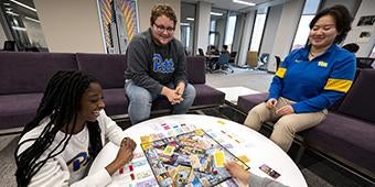 students gathered around coffee table playing Pittsburgh Monopoly