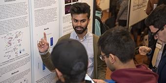 student showing research poster during science fair