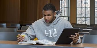 Student studying with textbook and digital tablet