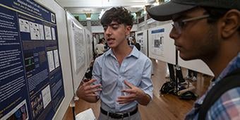 Participant shares research poster during Research and Creative Expressions Fair