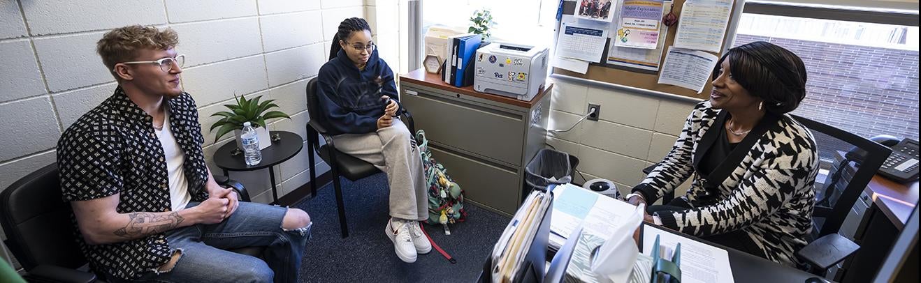 Two students speak with an advisor in her office on the Pitt-Bradford campus.